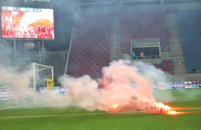 Brann-supportere kastet en rekke bluss ut på banen, og noen i Vålerenga-svingen svarte med å tenne på et Brann-flagg. Kampen ble stoppet i cirka fire minutter mens banen ble ryddet. Foto: André Kjernsli Brann-supportere kastet en rekke bluss ut på banen, og noen i Vålerenga-svingen svarte med å tenne på et Brann-flagg. Kampen ble stoppet i cirka fire minutter mens banen ble ryddet. Foto: André Kjernsli