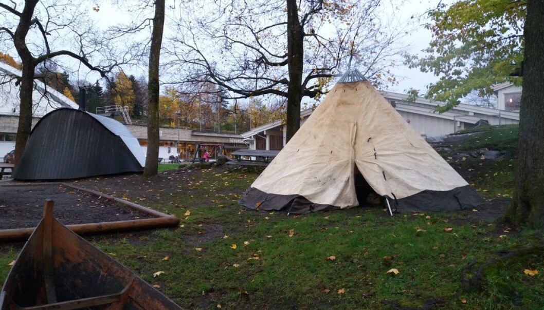 Høstbilde fra Samisk barnehage. Det hvite huset i bakgrunnen er barnehagen. På tunet: lávvu og goahti (tradisjonsbygg), tradisjonell båt og sandkasse. Høstbilde fra Samisk barnehage. Det hvite huset i bakgrunnen er barnehagen. På tunet: lávvu og goahti (tradisjonsbygg), tradisjonell båt og sandkasse.