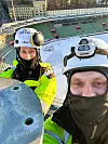 To arbeidere med verneutstyr står høyt over en snødekt stadiontribune