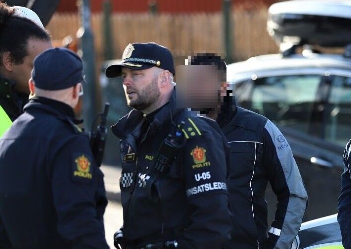 NOKAS-vekter (bak politiets innsatsleder) etter at familiefaren skal ha blitt lagt i bakken og skadet ved å få et kne plassert over halsen slik at han ikke fikk puste. Foto: André Kjernsli NOKAS-vekter (bak politiets innsatsleder) etter at familiefaren skal ha blitt lagt i bakken og skadet ved å få et kne plassert over halsen slik at han ikke fikk puste. Foto: André Kjernsli