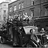 Jublende kvinner og barn med flagg kjører gjennom Oslos gater, mai 1945.