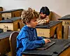 Elev gutt i busserull ved pult i Oslo skolemuseum Foto: Oslo kommune