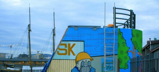 På havna fins en grå betongkloss lyst opp med en fargerik havnearbeider