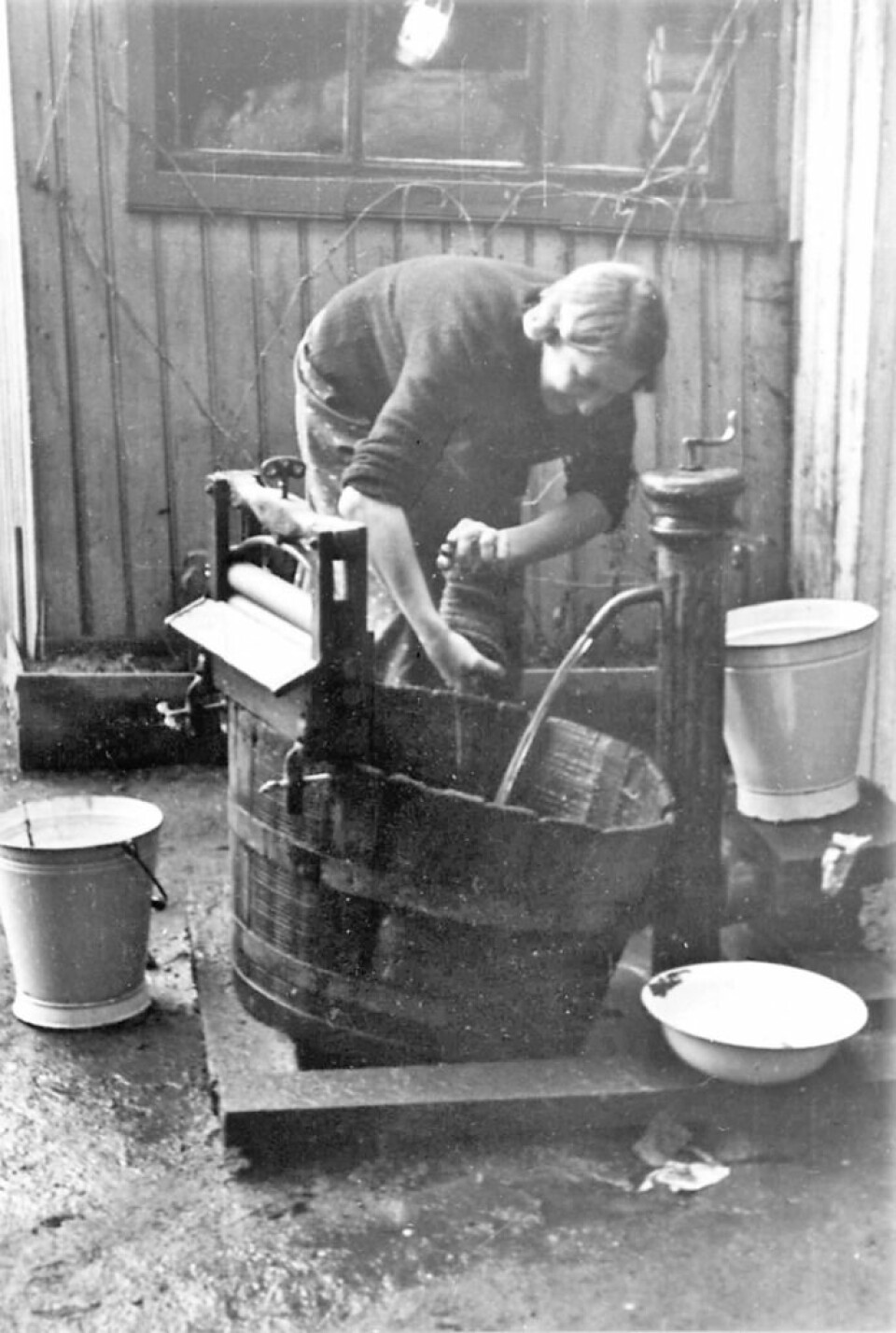 Kvinne vasker tøy utendørs, utstyrt med vannpost. Foto: Nanna Broch