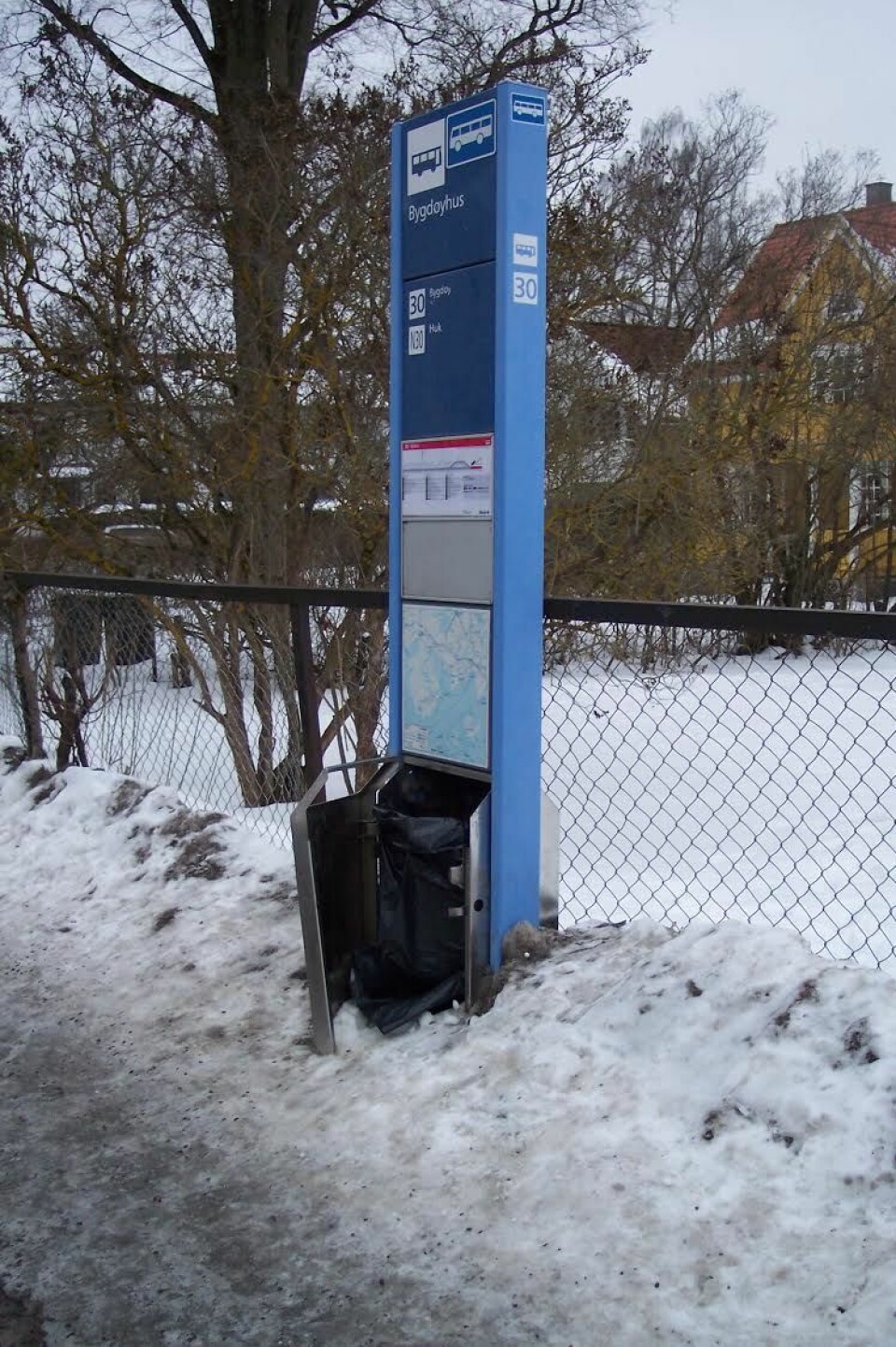 Is, snø og vandalisme. Søppelkassen ved 30-bussens stoppested Bygdøyhus fungerer dårlig. Foto: Jens Petter Rotnes