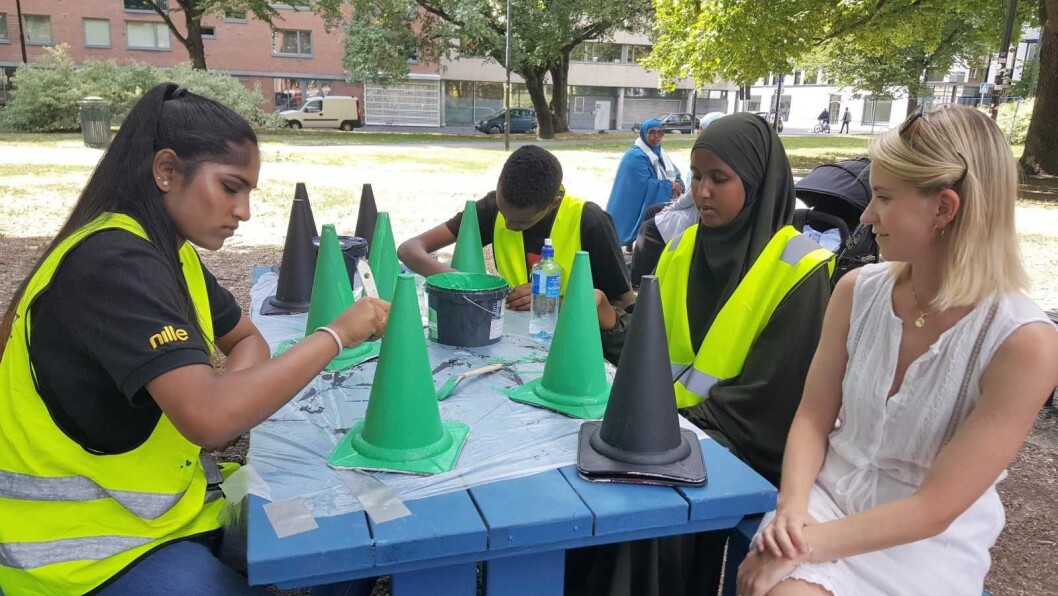 Fra venstre: ungdommene Asmitha (15) og Fuad (16) har sommerjobb, Nafisa (22) er assistent i gruppa og leder i Gamle Oslo bydelsutvalg, Line Oma tar en titt. Ungdommene lager Ludo-brikker til et stort gate-Ludo-spill på Rudolf Nilsens plass. Foto: Tarjei Kidd Olsen Fra venstre: ungdommene Asmitha (15) og Fuad (16) har sommerjobb, Nafisa (22) er assistent i gruppa og leder i Gamle Oslo bydelsutvalg, Line Oma tar en titt. Ungdommene lager Ludo-brikker til et stort gate-Ludo-spill på Rudolf Nilsens plass. Foto: Tarjei Kidd Olsen