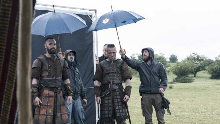 Den eksakte rollefiguren som Thea er i The Last Kingdom er hemmelig, men her ser vi at ikke en gang vikinger liker regn. Bjørn Bengtsson (Sigefrid) og Christian Hillborg (Erik) får VIP-behandling mellom opptak. Foto: Netflix Den eksakte rollefiguren som Thea er i The Last Kingdom er hemmelig, men her ser vi at ikke en gang vikinger liker regn. Bjørn Bengtsson (Sigefrid) og Christian Hillborg (Erik) får VIP-behandling mellom opptak. Foto: Netflix