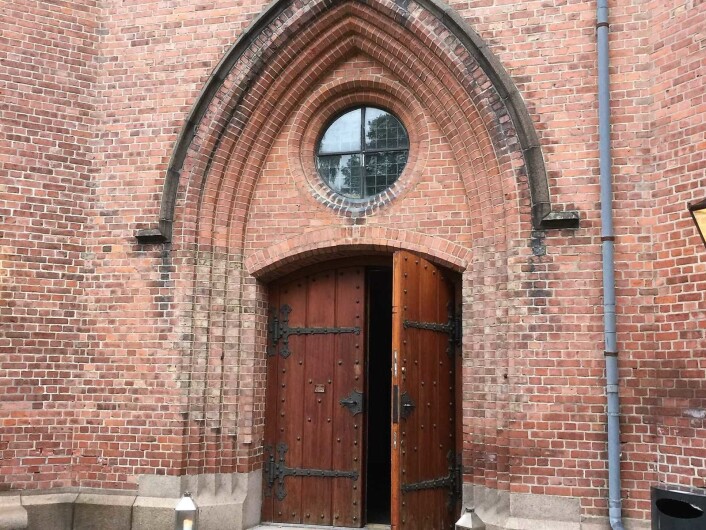 Rød teglstein og tunge tredører viser vei inn i kirken som skal ha 12.500 registrerte sognebarn. Foto: Kjersti Opstad Rød teglstein og tunge tredører viser vei inn i kirken som skal ha 12.500 registrerte sognebarn. Foto: Kjersti Opstad