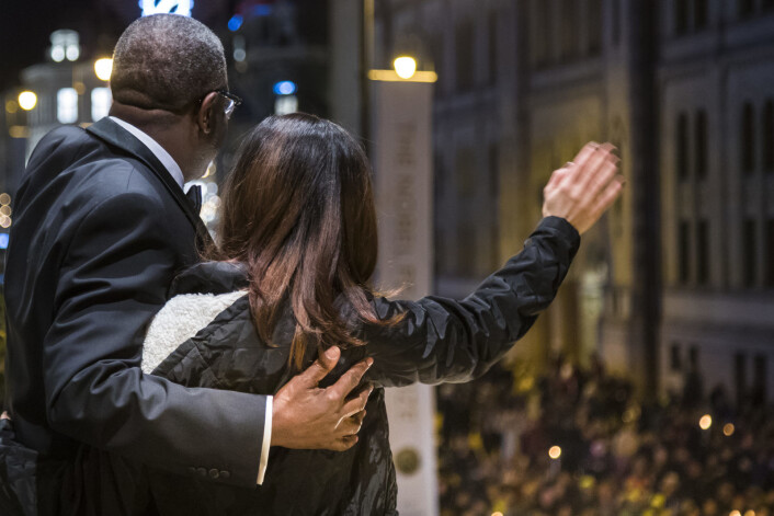 Denis Mukwege og Nadia Murad vinker til fakkeltoget fra balkongen på Grand Hotel mandag. Tidligere på dagen mottok de Nobels fredspris i Oslo rådhus. Murad fra Irak og Mukwege fra Kongo tildeles Nobels fredspris for sin kamp mot seksualisert vold brukt som våpen i krig og væpnede konflikter. Foto: Heiko Junge / NTB scanpix Denis Mukwege og Nadia Murad vinker til fakkeltoget fra balkongen på Grand Hotel mandag. Tidligere på dagen mottok de Nobels fredspris i Oslo rådhus. Murad fra Irak og Mukwege fra Kongo tildeles Nobels fredspris for sin kamp mot seksualisert vold brukt som våpen i krig og væpnede konflikter. Foto: Heiko Junge / NTB scanpix