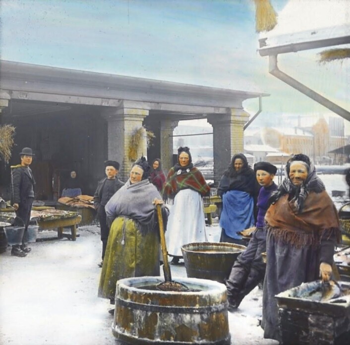 Fiskekoner ved Sadelmakerbrygga. Håndkolorert fotografi av Anders B. Wilse / Oslo museum Fiskekoner ved Sadelmakerbrygga. Håndkolorert fotografi av Anders B. Wilse / Oslo museum