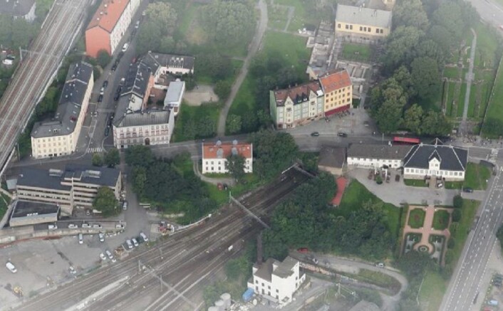 Slik var tomten, til venstre for det hvite huset midt i bildet, før trærne ble felt. Oslo Ladegård til høyre i bildet. Utsnitt av oversiktsfoto fra Reiulf Ramstad arkitekter Slik var tomten, til venstre for det hvite huset midt i bildet, før trærne ble felt. Oslo Ladegård til høyre i bildet. Utsnitt av oversiktsfoto fra Reiulf Ramstad arkitekter