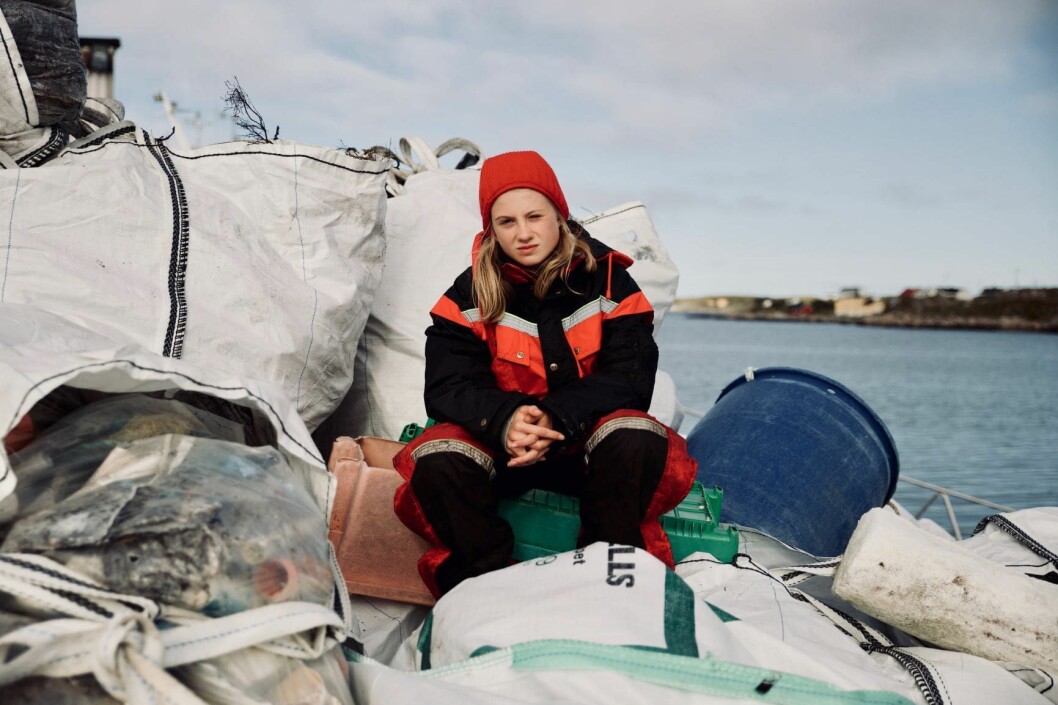Penelope Lea sitter på et berg av plastikk i Mausund. Foto: Hacienda Film og Differ Media