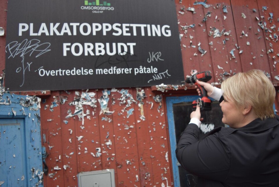 Byråd Marte Scharning Lund skrur ned skiltet med plakatforbud. Når det blir liv inne, blir det slutt på forsøplingen utenfor. Foto: Magnus Evenstuen