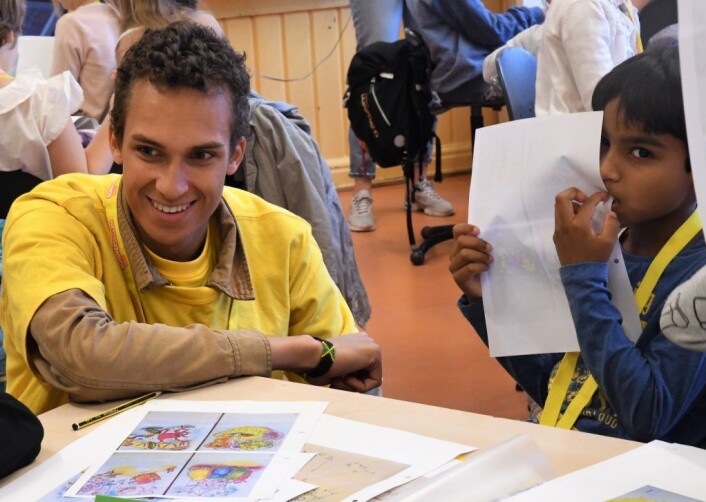 Sommerskoleleev Mohammed Ayman tar en bit tegningen, mens assistent Leon Mjaaland hjelpr en medelev. Foto: Christian Boger Sommerskoleleev Mohammed Ayman tar en bit tegningen, mens assistent Leon Mjaaland hjelpr en medelev. Foto: Christian Boger