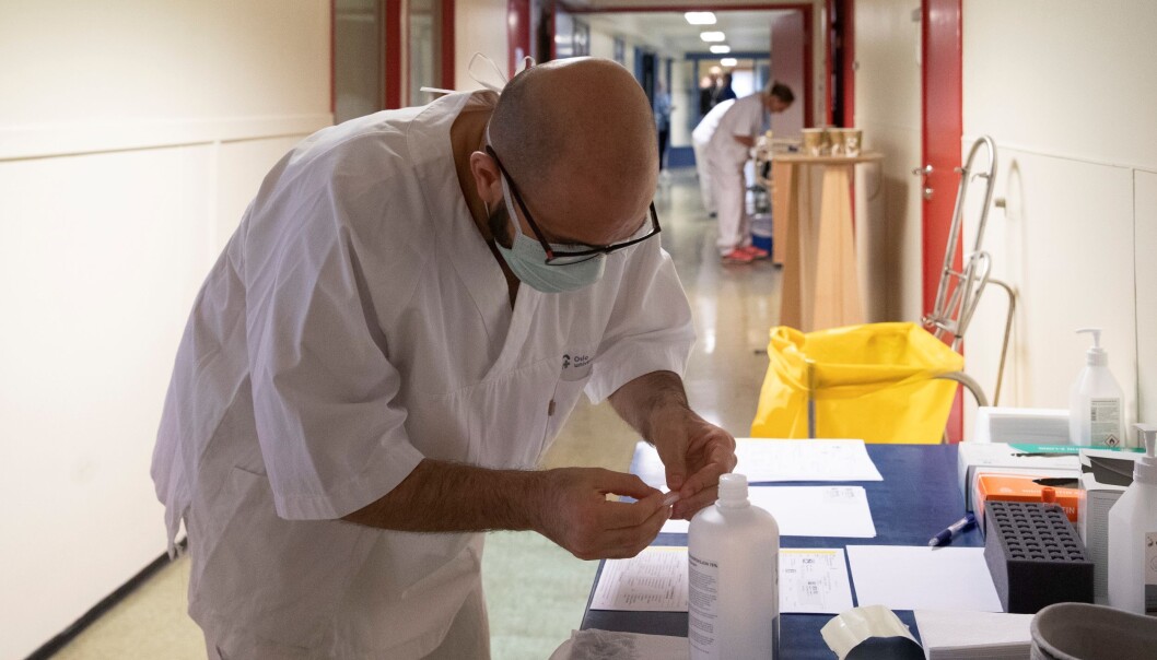 Bioingeniør Hassan Alhassani tar i mot en ny koronatest fra en av de ansatte ved Ullevål sykehus. Bioingeniør Hassan Alhassani tar i mot en ny koronatest fra en av de ansatte ved Ullevål sykehus.