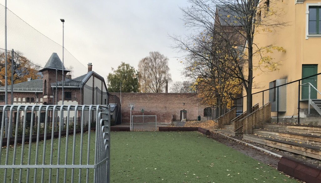 Skolens hovedbygninger ligger bak muren bakerst i bildet. Den lille ballbanen er også en del av skoleanlegget. Skolens hovedbygninger ligger bak muren bakerst i bildet. Den lille ballbanen er også en del av skoleanlegget.
