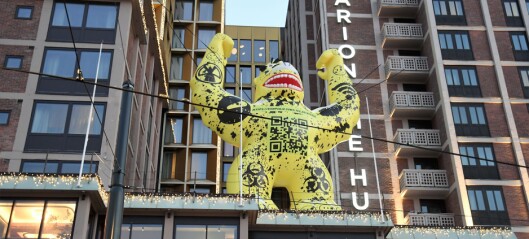 Et gedigent, gult godzilla-monster lyser mot Jernbanetorget fra hotelltaket på The Hub. Her er hvorfor