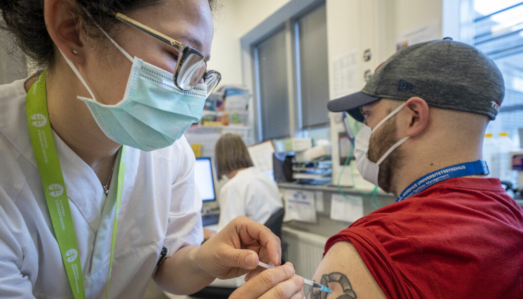 Portør Magnus Kinne får sin første sprøyte med Moderna-vaksine av sykepleier Andrea Navarrete på Vaksinasjonspoliklinikken ved Bedriftshelsetjenesten på Ahus.