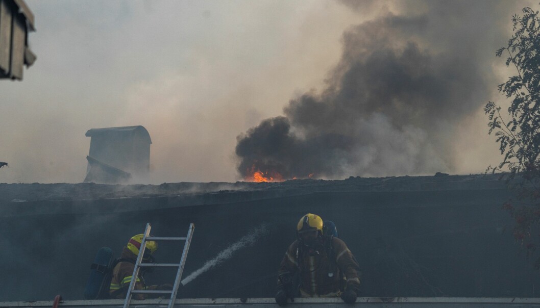 Brannfolk i røykdykkerutstyr på taket av rekkehuset som brant i Smiuveien på Stovner.