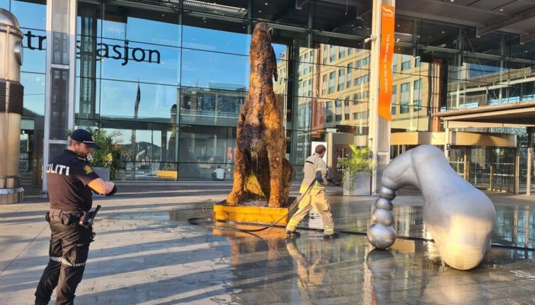 Brannvesenet etterslukker skulpturen av en ulende hund dekket av mose utenfor inngangen til Flytogterminalen og Oslo S. Brannvesenet etterslukker skulpturen av en ulende hund dekket av mose utenfor inngangen til Flytogterminalen og Oslo S.