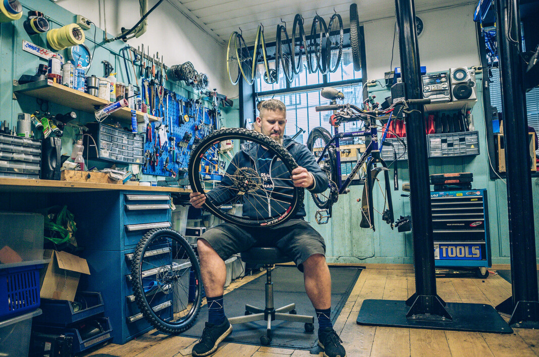 På sykkelverkstedet til Oslo Sportslager sitter Adam Marcin Jurasz og fikser et dekk.