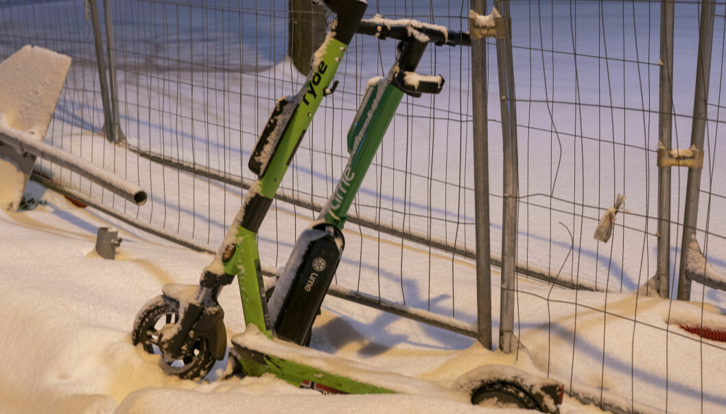 Elektriske sparkesykler står henslengt i snøen i Oslo sentrum.