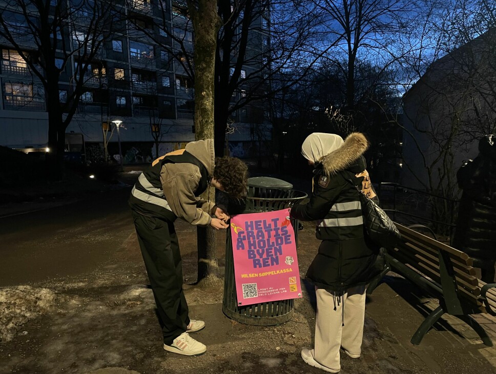 Juniorforskerne Julian Brito-Benestad og Hanan Zag henger opp plakater på Gartnerløkka ved Enerhaugblokkene.
