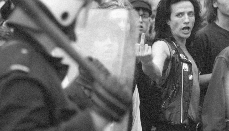 22. juni 1988: Rød Valgallianses aksjon «La ungdommen leve» arrangerte en lovlig friluftskonsert på Youngstorget om kvelden den 22. juni. Samme kveld gikk det et demonstrasjonstog fra torget til Fridtjof Nansens Plass foran Rådhuset. Blitz-demonstrant Stein Lillevolden ga uttrykk for hva han mente om politiet da det kom til sammenstøt mellom politi og noen av de flere hundre demonstrantene under demonstrasjonen i borggården. I august samme år informerte byråd Sigurd Østen at Blitz skulle rives og at det politiske vedtaket om riving skulle komme i løpet av høsten. Det resulterte i at Blitz-miljøet varslet krig mot politiet og politikerne. Foto: Henrik Laurvik / NTB