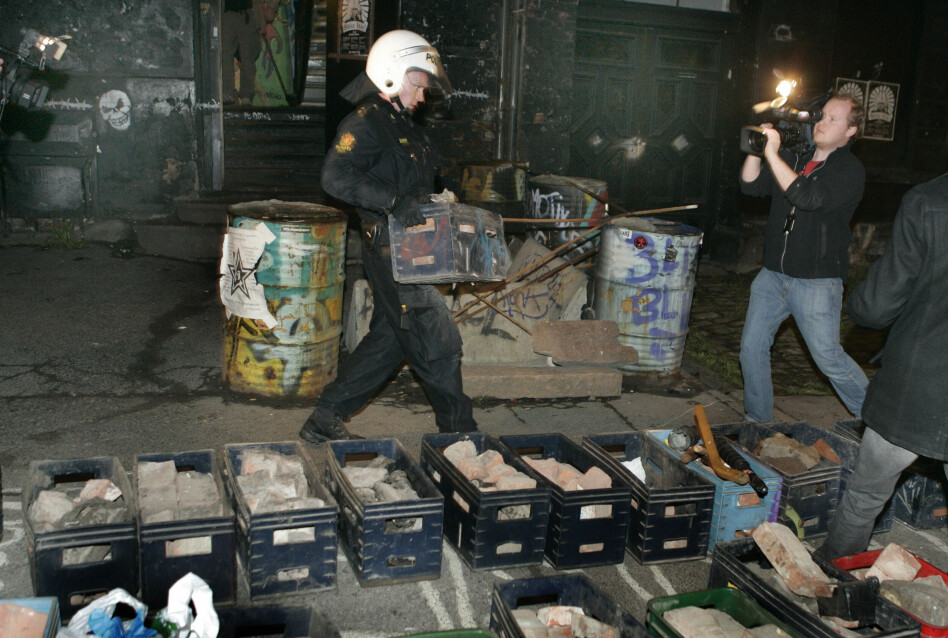 27. april 2007: Politiet aksjonerte mot blitzhuset i Pilestredet og bar melkekasser med det NTB kaller «kastevåpen» ut av huset. Politimann med hjelm. Kameramann med TV kamera th. i bildet. Foto: Knut Falch / NTB