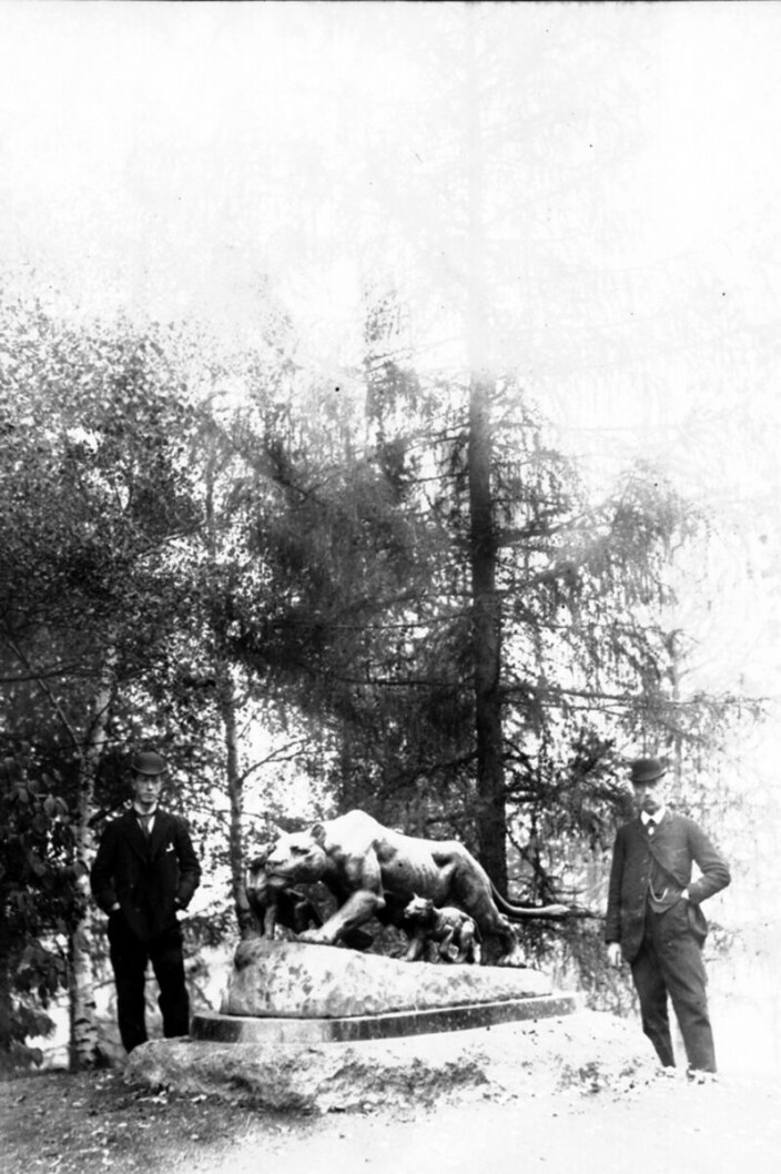 Foto av skulpturen i parken fra ca. 1892. To menn i dress og bowler ved siden av. Foto av skulpturen i parken fra ca. 1892. To menn i dress og bowler ved siden av.