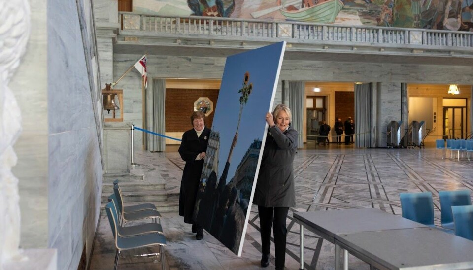 Marianne Borgen og Kjersti Fløgstad har kommet frem til Rådhushallen med ett av bildene fra Fredsprisutstillingen.