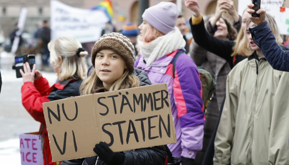 Greta Thunberg med plakat der det står at 'vi saksøker staten'.
