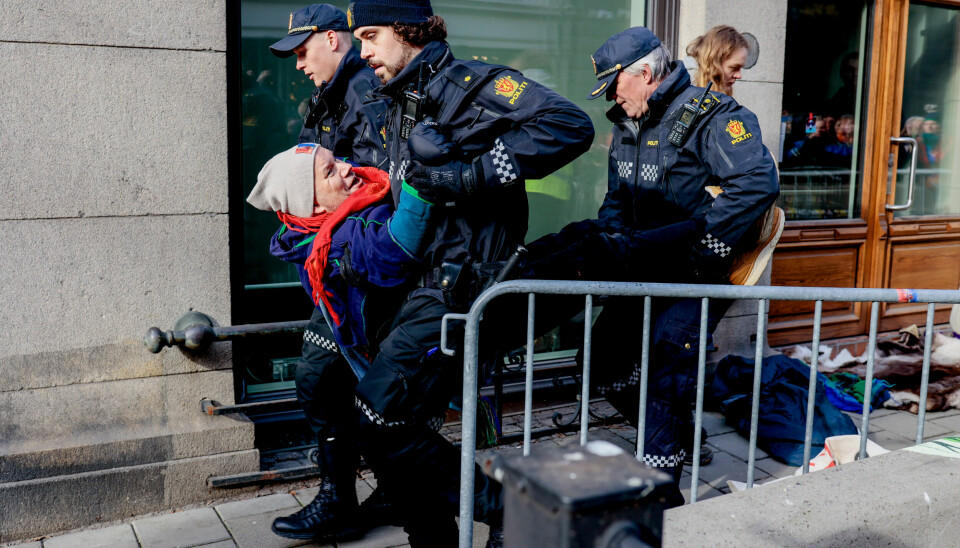Oslo 20230302. Aksjonister bæres bort av politiet fra inngangen til Nærings- og fiskeridepartementet i protest mot at vindturbinene på Fosen, som Høyesterett har sagt at er ulovlige, ikke er revet.