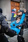 En demonstrant blir bært bort av politiet.
