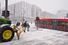 Traktor med snøskjær i snøvær mens buss kjører i kryss i Bjørvika.