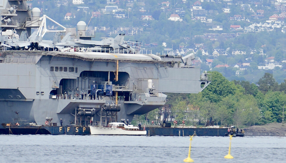 Kronprins Haakon besøkte fredag det amerikanske hangarskipet USS Gerald R. Ford i Bunnefjorden. Her ser vi den forholdsvis knøttlille hvite båten som fraktet kronprinsen ut til skipet, som er verdens største krigsskip og skal ligge i havn i Oslo i fire dager.