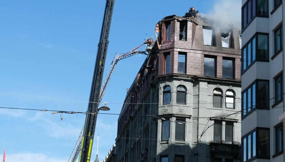 Brannen som startet på takterrassen søndag kveld har etterlatt stor skade på bygningen i Grensen. Tirsdag ettermiddag meldes det at brannen skal være under kontroll. Her et bilde fra stedet mandag.