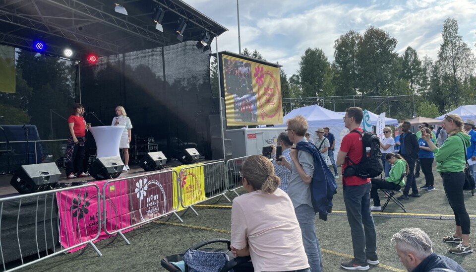 Folk følger med på politisk duell mellom ordførerkandidatene på Mortensrud Festival. På scenen står Aps Rina Mariann Hansen og Høyres Anne Lindboe.