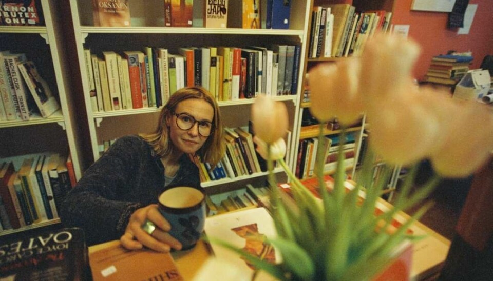 Kvinne sitter ved et bord i en bokbutikk.