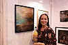 Kunstner Trudy Wiegand som har bidratt to år på rad med kunst til flaskeetikett. Her poserer hun med både kunstverket og flasken som har fått kunsten på sin etikett