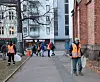 Mennesker i oransje vesker plukker søppel.