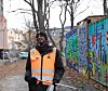 Mann står i oransje vest med plukke-verktøy i hånden.