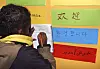 Jente står ved døren til klasserommet sitt. Skriver i bok. Skole. Skolen. Elev. Elever. Grunnskolen. Barneskolen. På døren står det velkommen på 17 forskjelling språk. Koreansk. Serbisk. Kinesisk osv. Like mange nasjonaliteter som de er i klassen. Integrering. Fremmedkulturelle. Flerspråklige. Språk. Språkundervisning. Morsmål. Morsmålsundervisning.