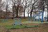 Blå treningsapparater i Galgeberg park. Underlag av utkuttede matter av kunstgress som ikke har samme fargetone som resten av parken. Apparatene tar opp store deler av parken.